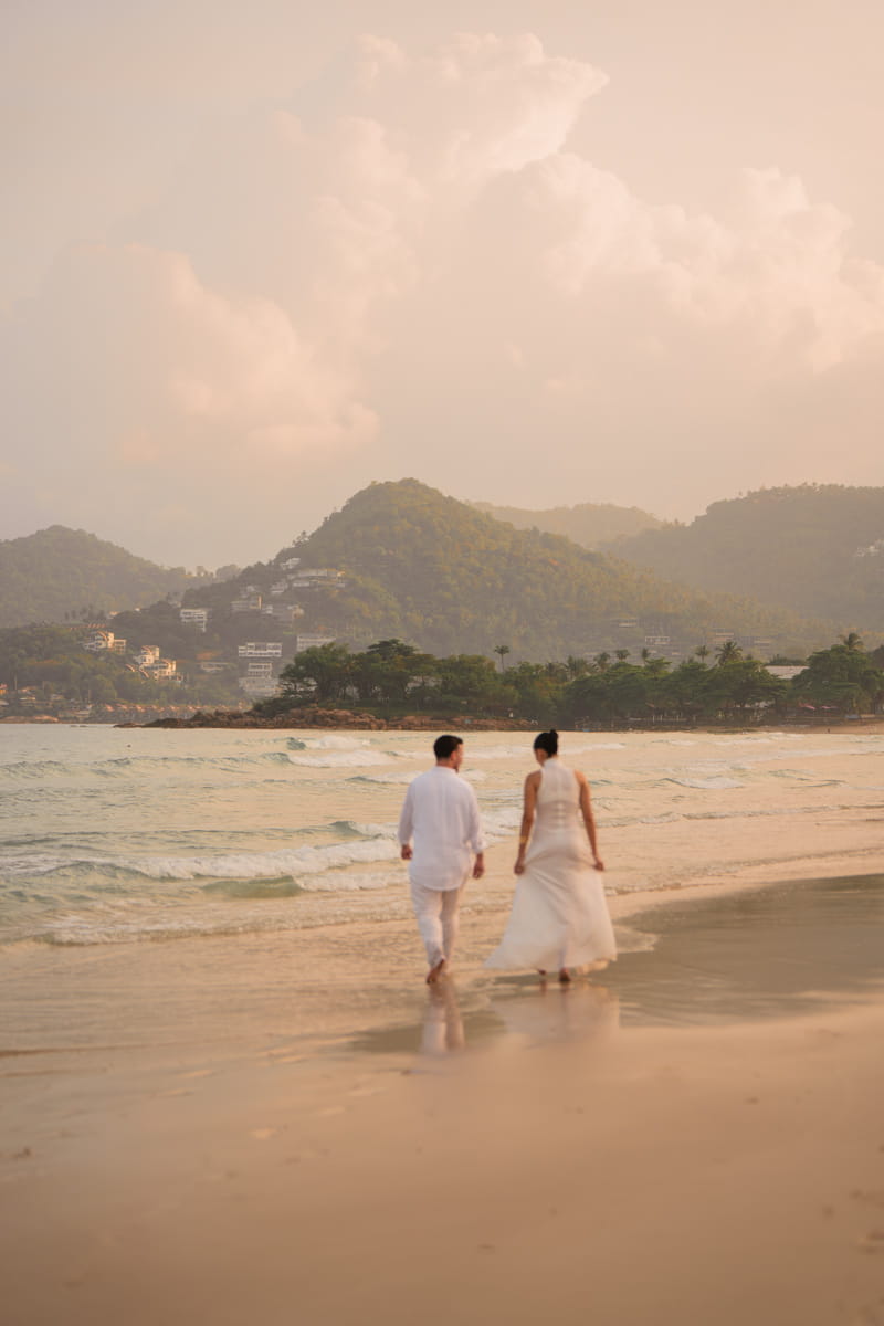 Couple walking along the beach after their wedding